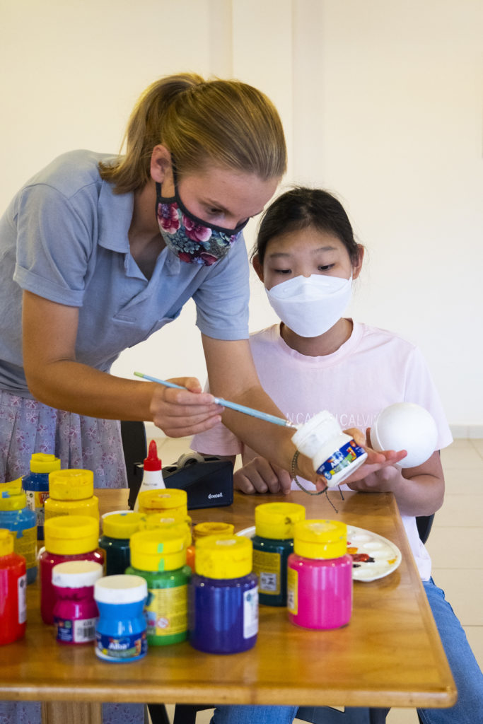 Teacher and student paint foam balls to create a miniature solar system